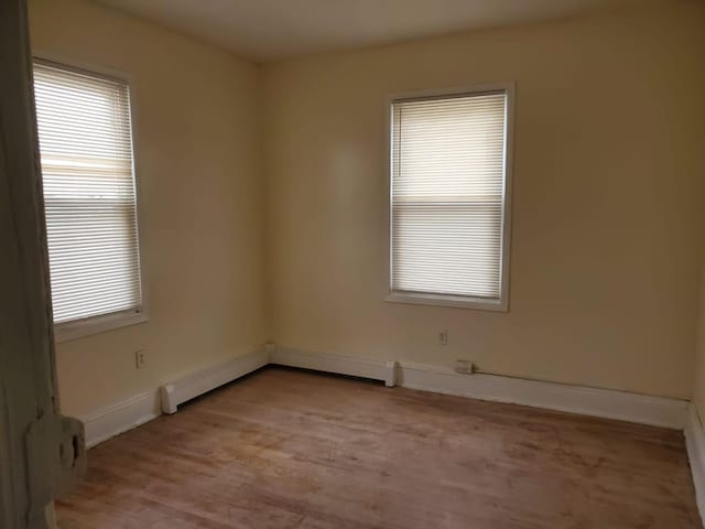 unfurnished room with a baseboard radiator and light hardwood / wood-style floors