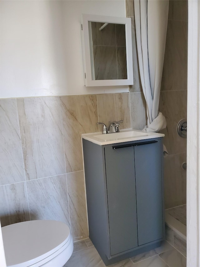 bathroom with tile walls, vanity, and toilet