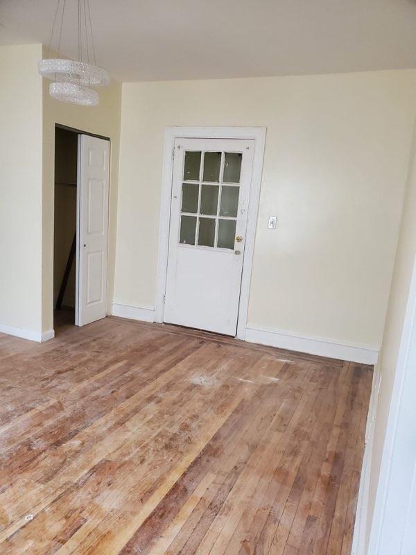 spare room with hardwood / wood-style flooring and an inviting chandelier