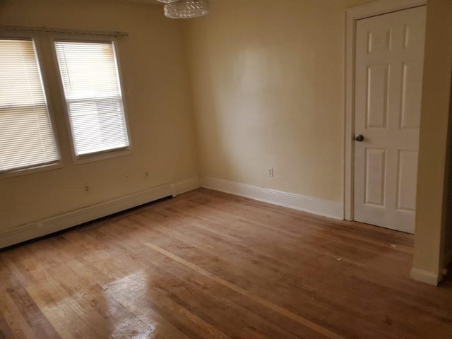 empty room with a baseboard heating unit and light hardwood / wood-style floors