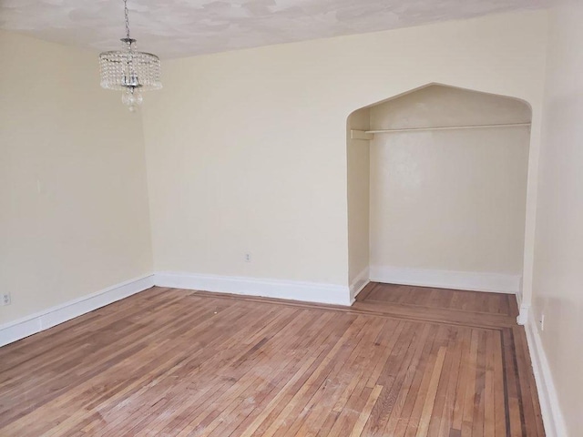 unfurnished room featuring a notable chandelier and hardwood / wood-style floors