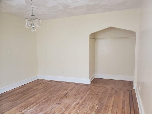 spare room with a notable chandelier and hardwood / wood-style floors