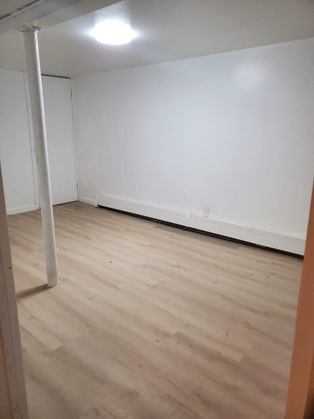 basement with baseboard heating and light wood-type flooring