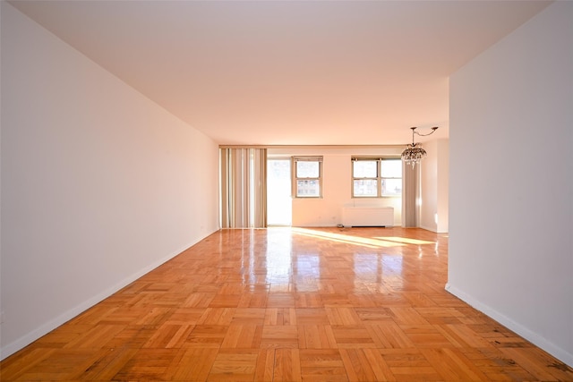 empty room with light parquet flooring and an inviting chandelier