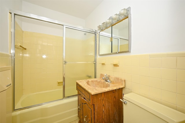 full bathroom with shower / bath combination with glass door, vanity, tile walls, and toilet