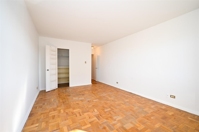 unfurnished bedroom featuring a walk in closet and light parquet floors