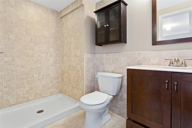 bathroom featuring vanity, tile patterned floors, toilet, tiled shower, and tile walls