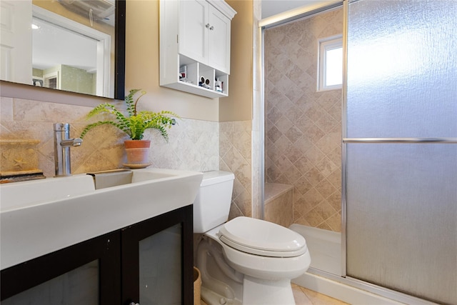 bathroom with tile patterned floors, vanity, tile walls, toilet, and a shower with shower door