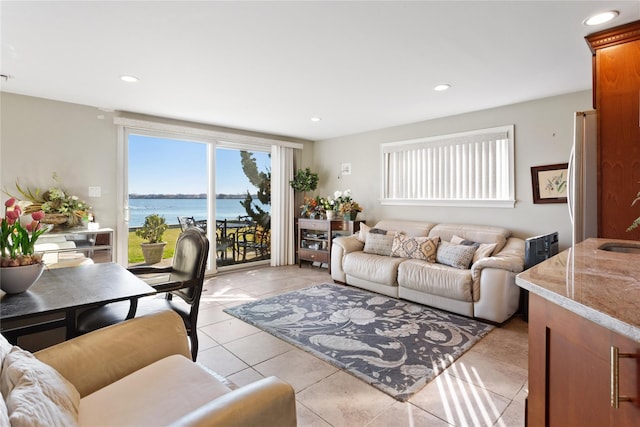 living room with light tile patterned floors, a water view, and sink