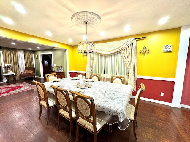 dining area with dark hardwood / wood-style floors and an inviting chandelier