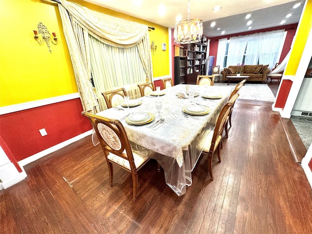 dining space with dark hardwood / wood-style floors and a notable chandelier