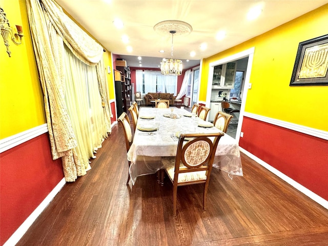 dining area featuring dark hardwood / wood-style flooring and an inviting chandelier