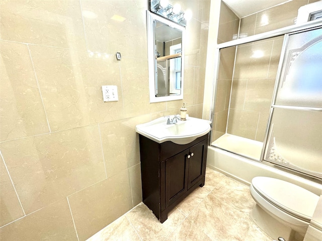 full bathroom featuring combined bath / shower with glass door, vanity, tile walls, and toilet