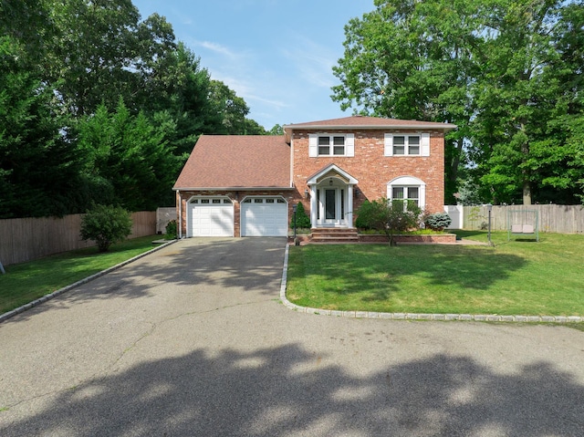 colonial inspired home featuring a garage and a front lawn