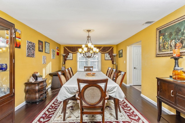 dining room with dark hardwood / wood-style flooring and an inviting chandelier