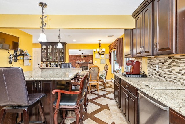 kitchen featuring stainless steel dishwasher, dark brown cabinetry, and a breakfast bar area