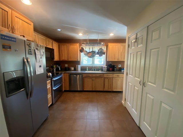 kitchen featuring appliances with stainless steel finishes, dark tile patterned flooring, light brown cabinets, and sink