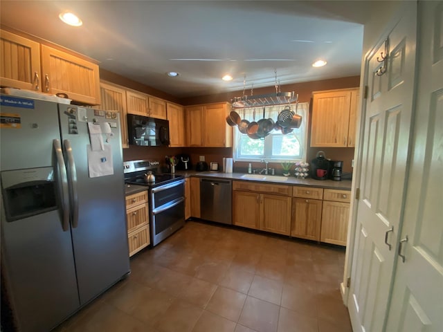 kitchen with stainless steel appliances, sink, decorative light fixtures, light brown cabinets, and tile patterned floors