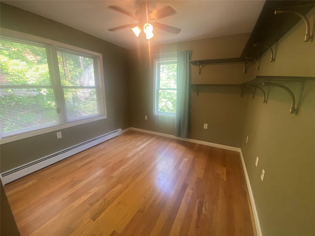 unfurnished room with light hardwood / wood-style floors, ceiling fan, and a baseboard heating unit