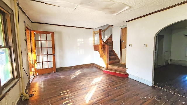 empty room featuring dark hardwood / wood-style floors, crown molding, and a textured ceiling