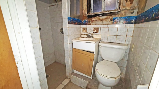 bathroom featuring tile patterned floors, vanity, tile walls, and toilet