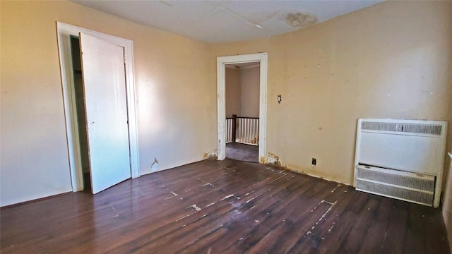 unfurnished bedroom with dark wood-type flooring and heating unit