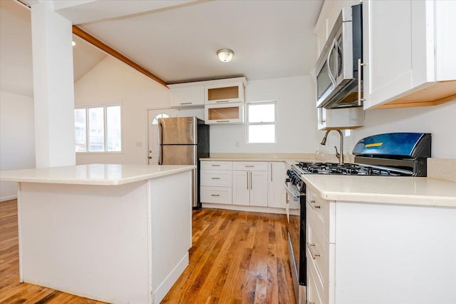 kitchen with stainless steel appliances, white cabinetry, plenty of natural light, and light hardwood / wood-style floors