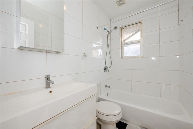 full bathroom featuring tile walls, vanity, tiled shower / bath combo, and toilet