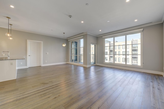 unfurnished living room with crown molding, dark hardwood / wood-style floors, and sink