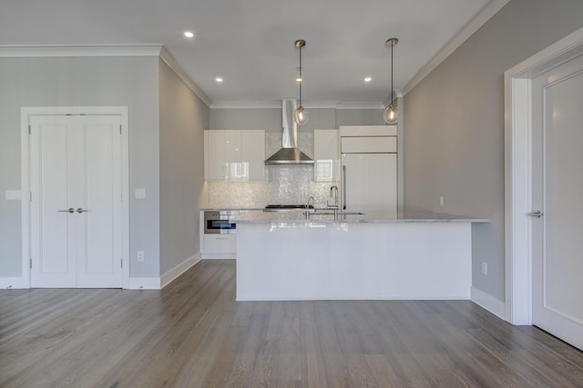 kitchen with pendant lighting, white cabinetry, backsplash, paneled built in fridge, and wall chimney exhaust hood