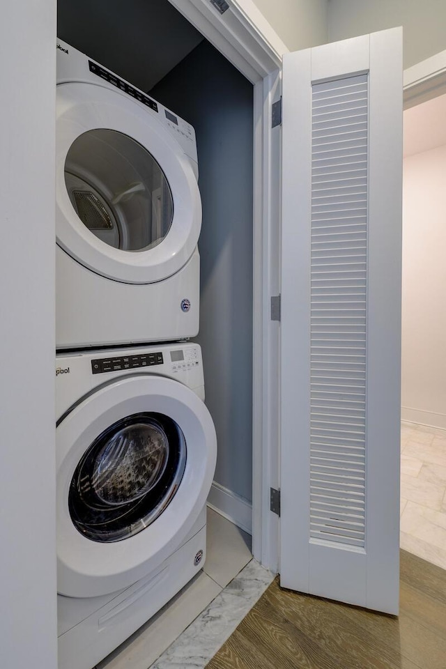 washroom with stacked washer and dryer and wood-type flooring