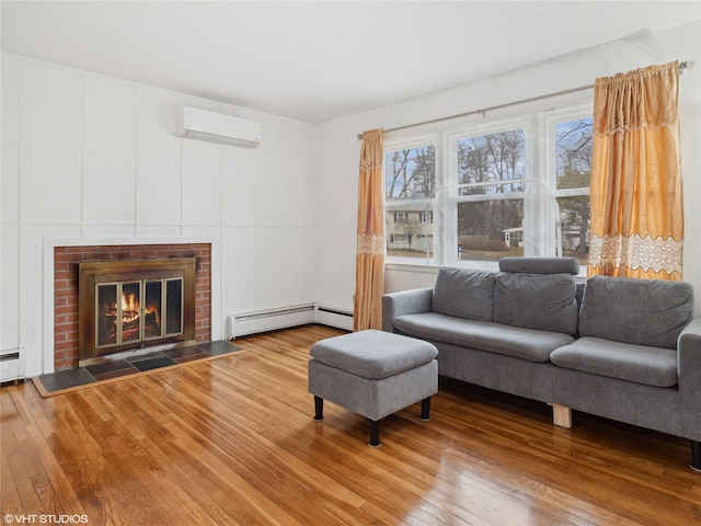 living room featuring a wall unit AC, baseboard heating, hardwood / wood-style floors, and a brick fireplace