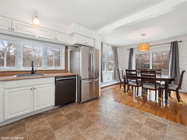 kitchen featuring a baseboard radiator, dishwasher, stainless steel refrigerator, pendant lighting, and sink