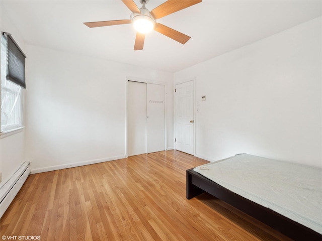 unfurnished bedroom featuring ceiling fan, baseboard heating, a closet, and light hardwood / wood-style floors