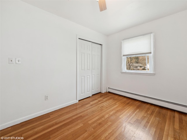 unfurnished bedroom with ceiling fan, a closet, light wood-type flooring, and a baseboard radiator