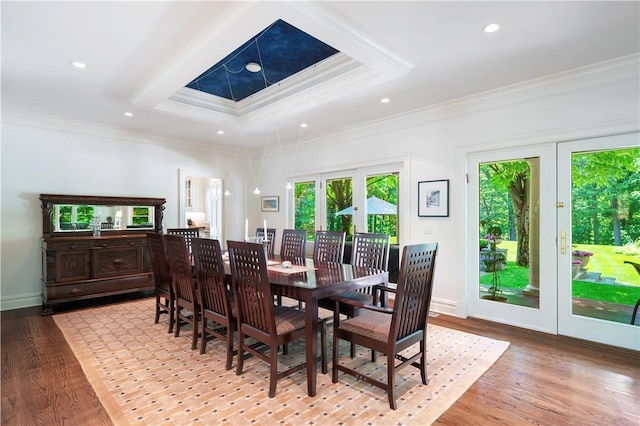 dining area with crown molding, a raised ceiling, and hardwood / wood-style flooring