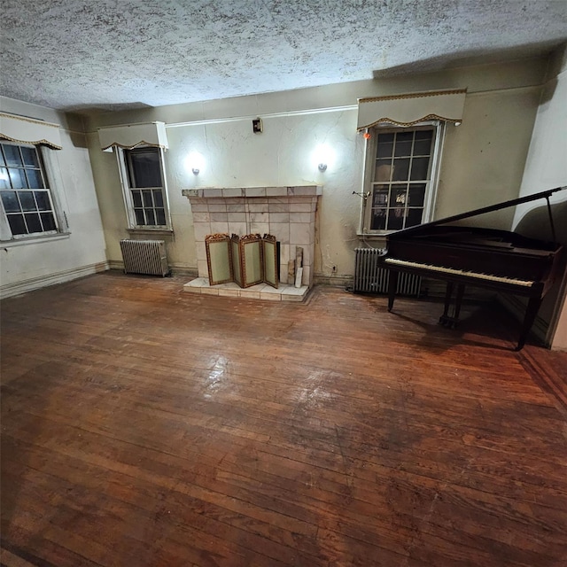 living room with a fireplace, a textured ceiling, radiator heating unit, and dark hardwood / wood-style floors