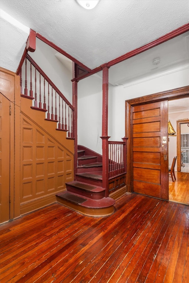 staircase featuring hardwood / wood-style floors and a textured ceiling