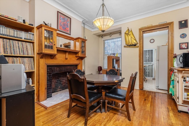 dining room featuring crown molding, a fireplace, and light hardwood / wood-style floors