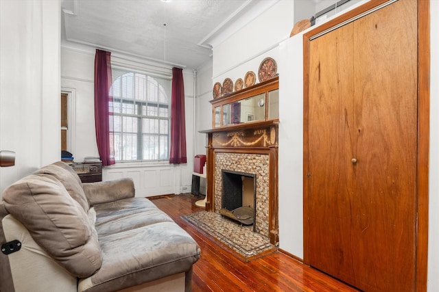 living room with hardwood / wood-style flooring, ornamental molding, a fireplace, and a textured ceiling