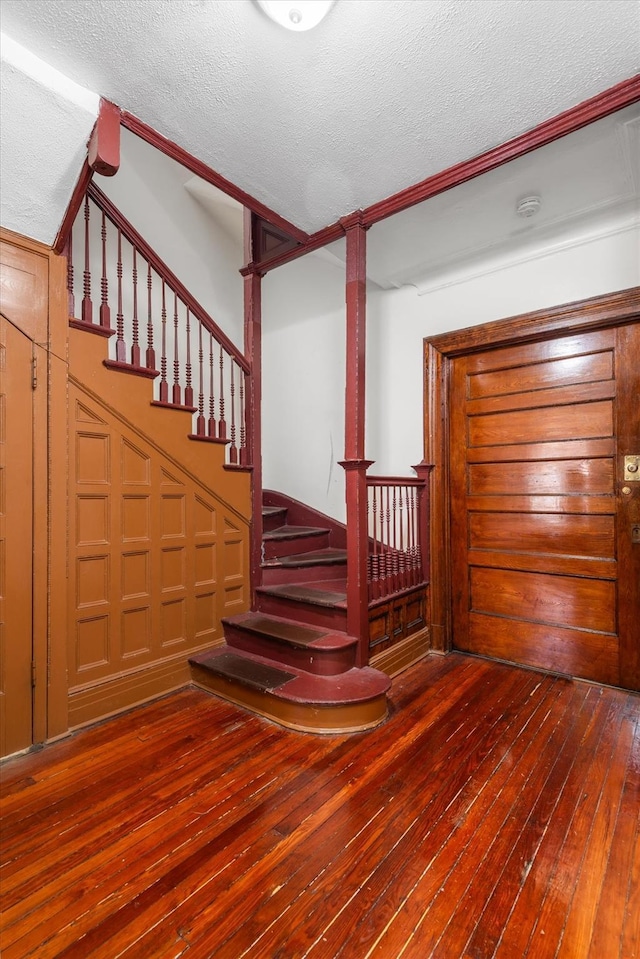 stairway with hardwood / wood-style flooring and a textured ceiling