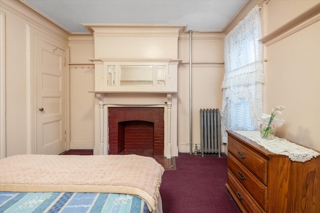 bedroom with dark colored carpet, ornamental molding, radiator, and a brick fireplace