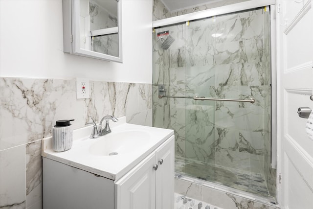 bathroom featuring vanity, a shower with door, and tile walls