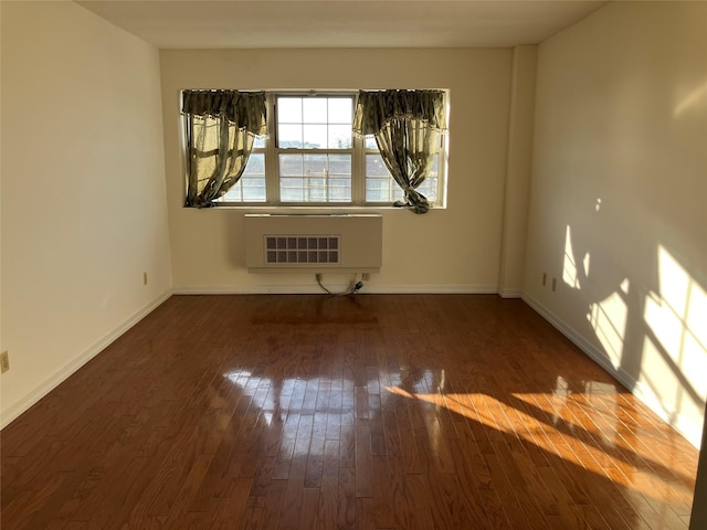 empty room with heating unit and dark wood-type flooring