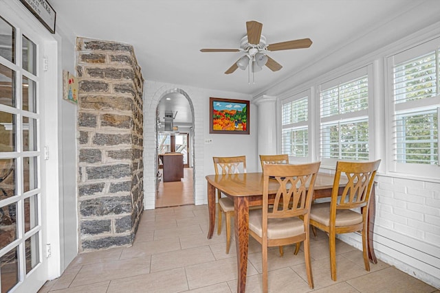 dining room featuring light tile patterned floors, ceiling fan, and brick wall