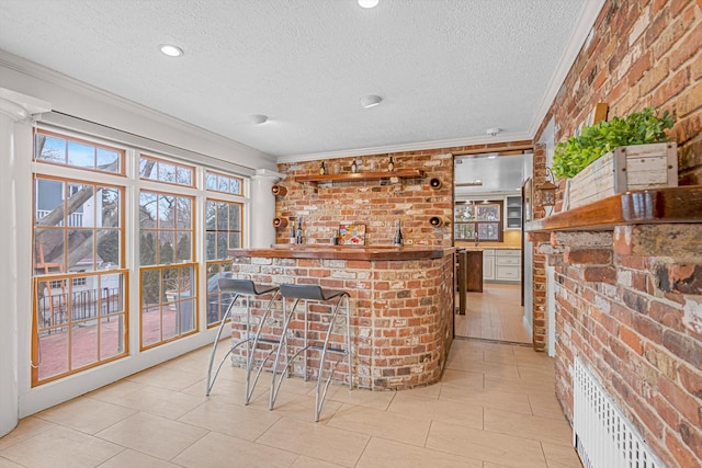 bar with crown molding, light tile patterned flooring, a textured ceiling, and brick wall