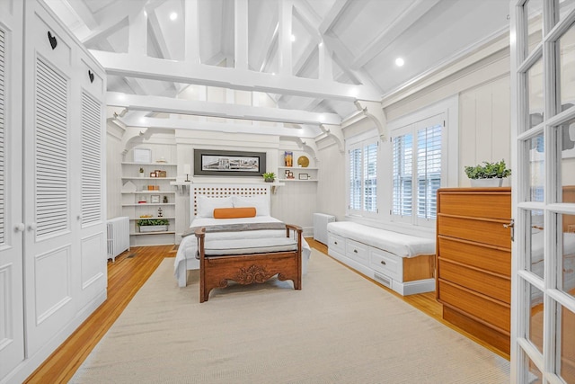 bedroom with radiator, lofted ceiling with beams, and light wood-type flooring