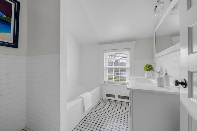 bathroom featuring a bathing tub, tile walls, and vanity