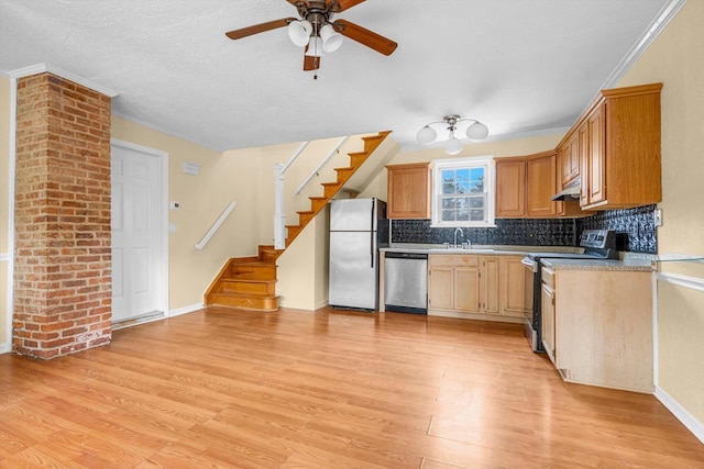 kitchen featuring appliances with stainless steel finishes, tasteful backsplash, sink, light hardwood / wood-style floors, and crown molding