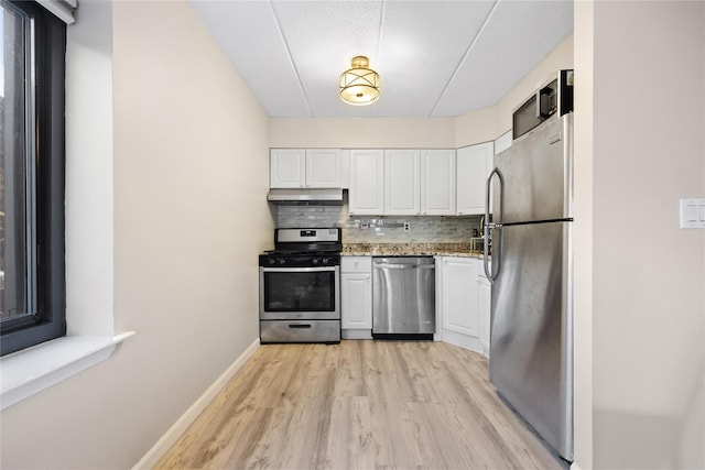 kitchen with stone counters, white cabinetry, tasteful backsplash, light hardwood / wood-style floors, and appliances with stainless steel finishes